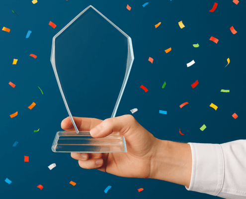 Hand holding a glass tourism award trophy with confetti falling, symbolizing recognition and success in the travel industry